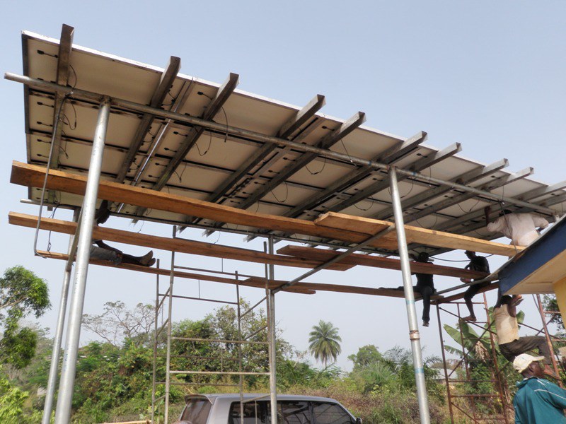 Engineers fitting solar panels to an overhead canopy structure