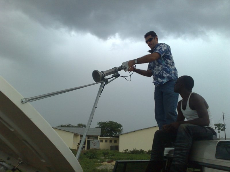 Engineer aligning a vehicle-mounted satellite antenna